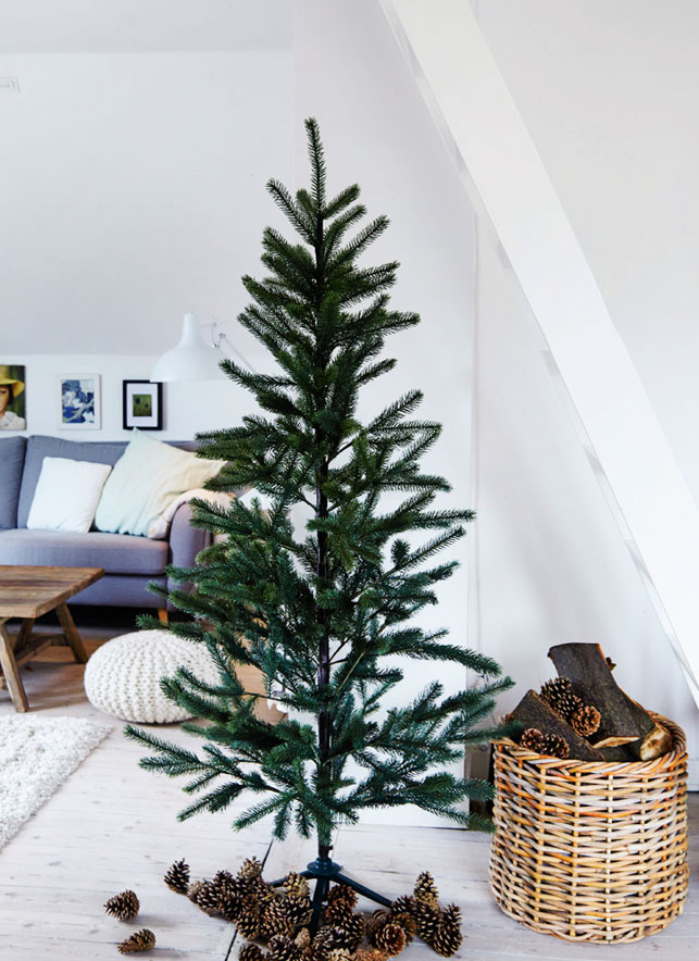 Christmas trees with no decor are a trend, and pinecones and firewood in the basket add a cozy touch