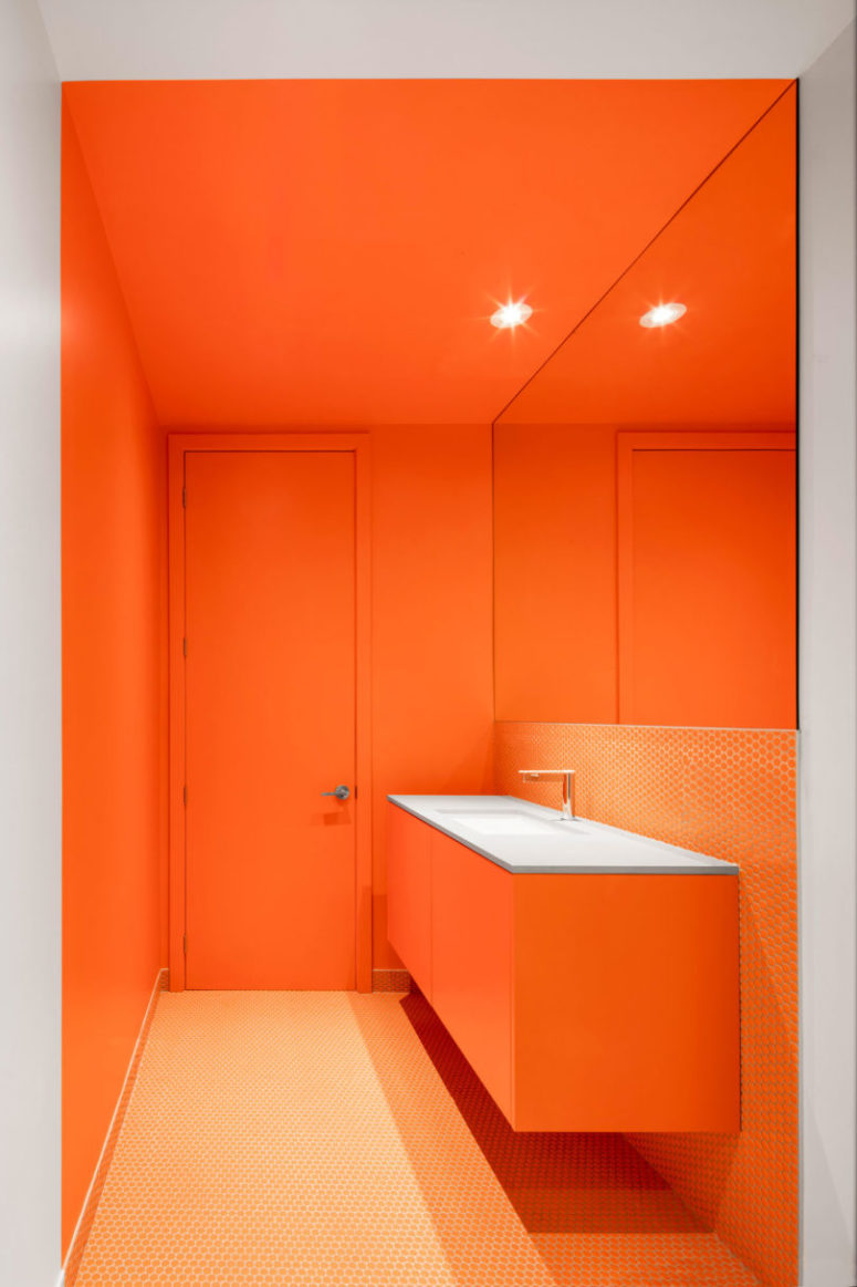 One of the bathrooms features bright orange and penny tiles, the space looks very bold