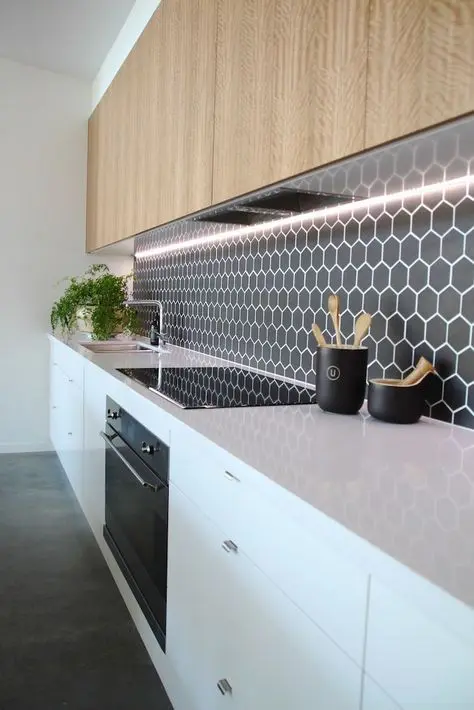 black hex tile backsplash with white grout contrasts with warm wood cabinets