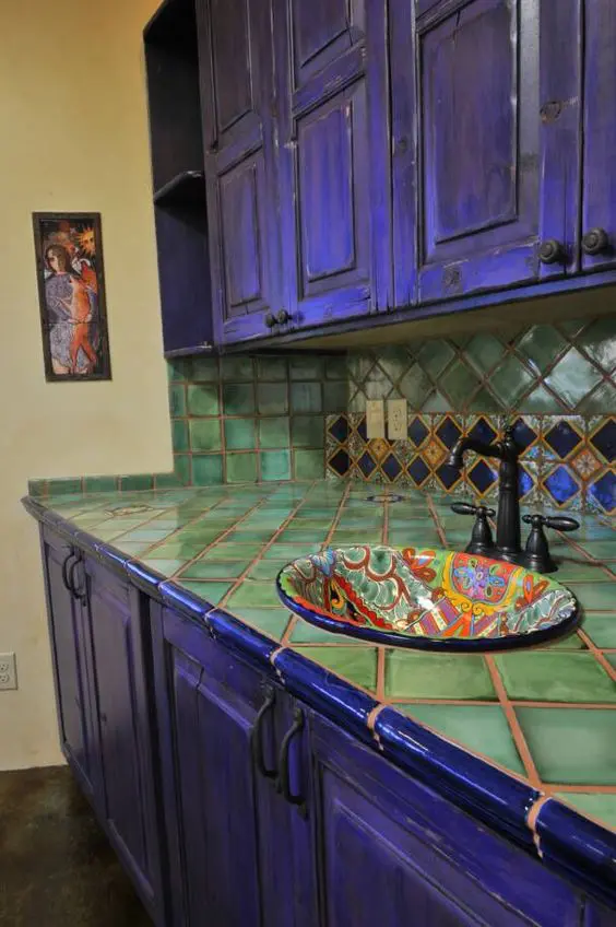 bold violet kitchen cabinets and green tiles on the backsplash and countertop