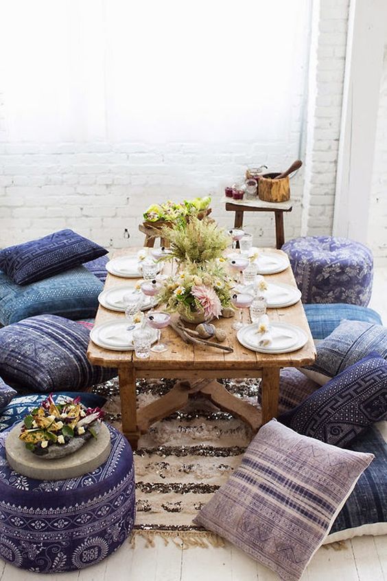 low picnic table with Moroccan-styled pilows and ottomans for guests