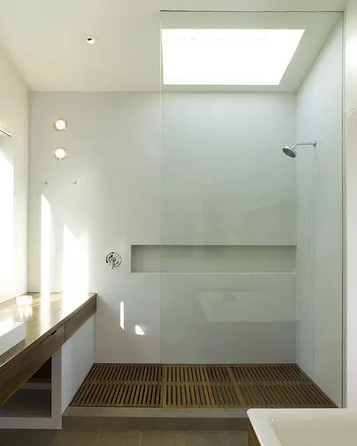 Spa like walk in shower with a wooden floor and a built in niche