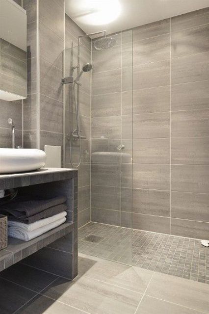 brown grey bathroom with the same tiles in the shower and a different floor