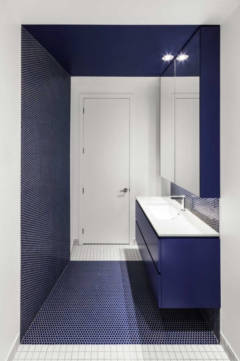 Another bathroom features the same penny tiles in navy color, again mixed with crispy white tiles