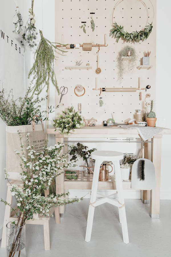 The crafting nook features beige and blush furniture and lots of greenery and flowers