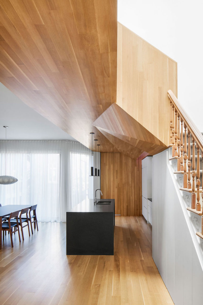 The geometrical ceiling covered with warm woods is a focal point of the kitchen and dining area