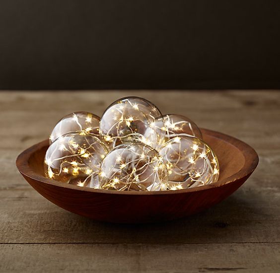 a wooden bowl with glass globes with string lights inside