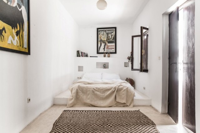 The bed in the master bedroom is placed onto a concrete platform, and an ethnic rug is a cool idea