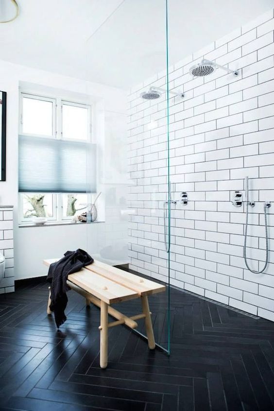 subway tiles with black grout and dark chevron-clad floors