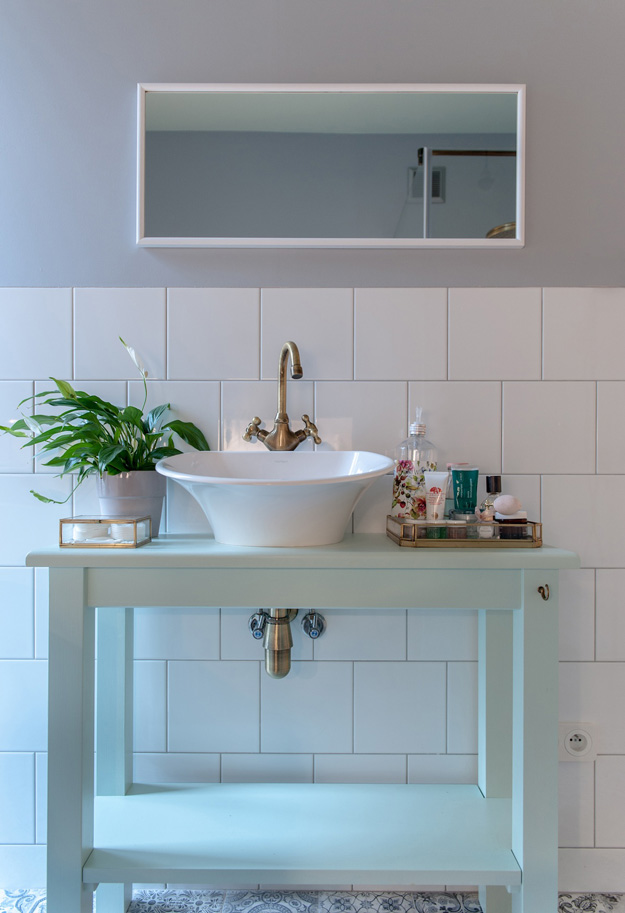 The bathroom counter is mint-colored, and gold touches make the space more refined
