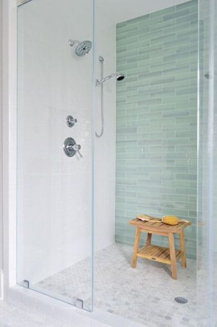 Glass enclosed shower with a green tile accent wall