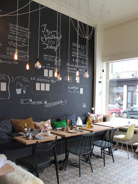 modern and cheerful coffee shop decor with a chalkboard wall and hanging bulbs