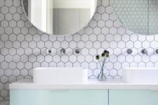 17 white hex tiles with black grout contrast with mint cabinets