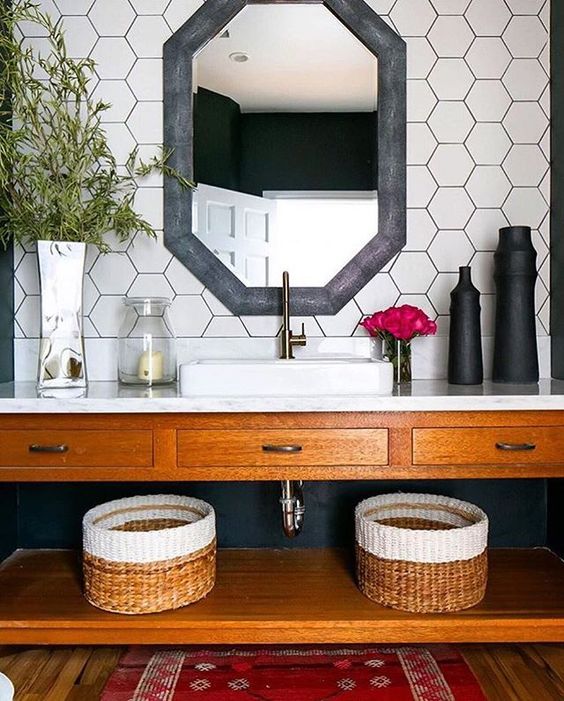 white hex tiles on the walls with black grout and a black framed mirror