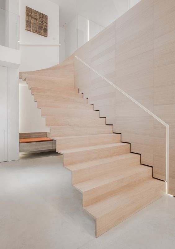 floating wooden staircase wwith a handrail cut in the plywood wall