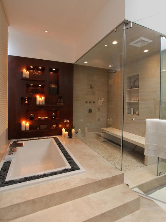 a large steam room with a bench opens to a sunken bathtub with stone lining