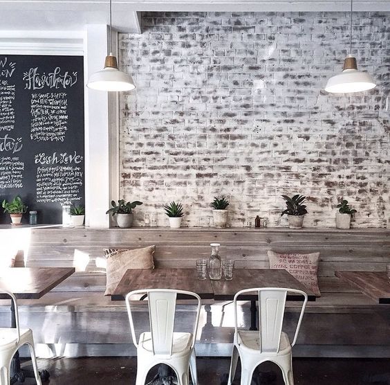 Whitewashed brick walls, rough wood tables and metal chairs
