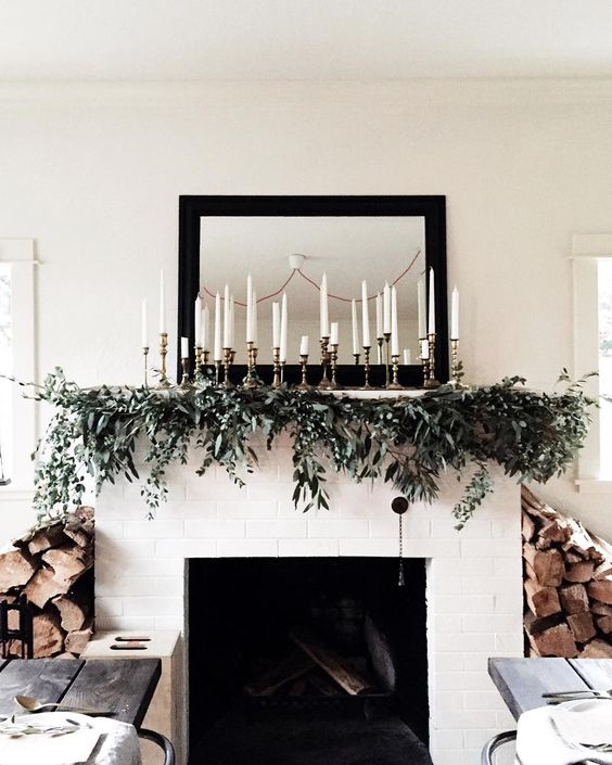 a greenery garland with lots of candles over the mantel