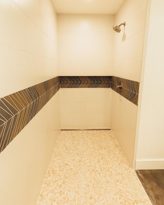 extra-large, cream-colored tiles cover the walls, and small, neutral tiles cover the floors