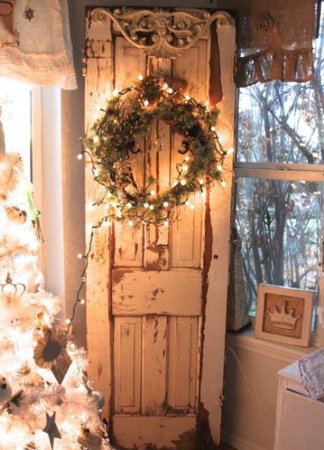 shabby chic door inside the house with a lit up wreath of greenery