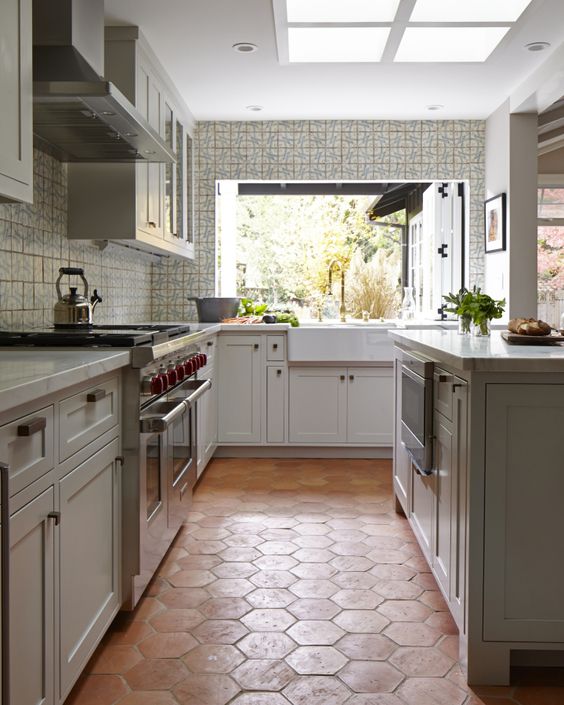 Red large hex tiles on the floor in a light colored kitchen