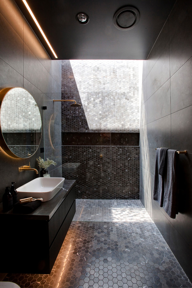 this moody dark bathroom features lots of tiles shades to highlight its floor and a shower wall (Urban Circuit Pty Ltd)