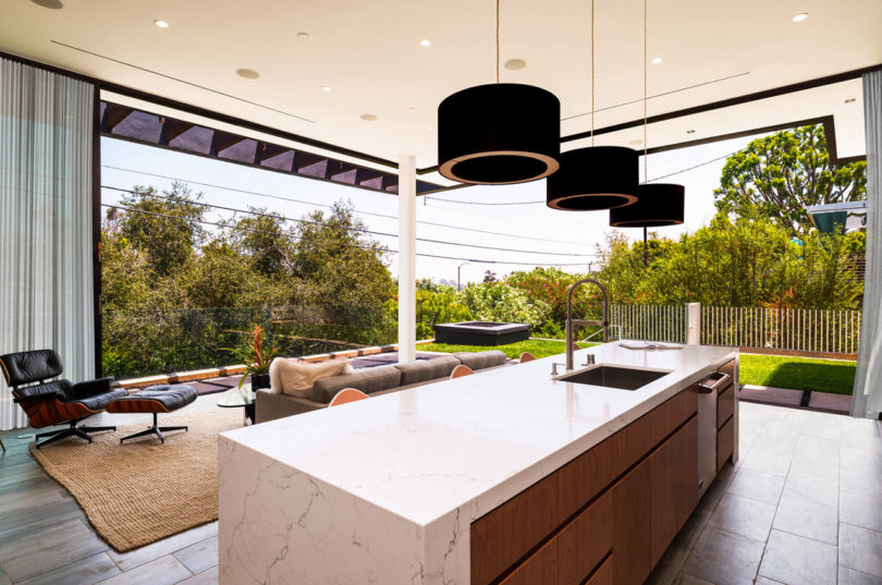 The kitchen is decorated in light-colored warm wood, marble surfaces and can be partly opened to outdoors