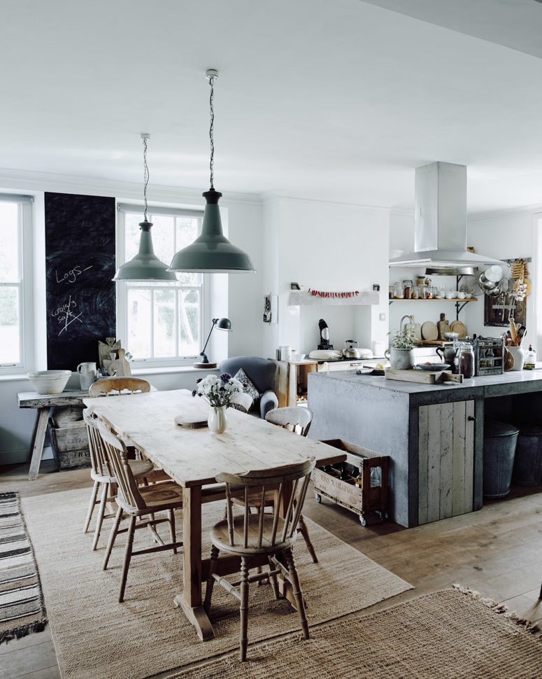 The kitchen is filled with light, the working surfaces are metal and concrete,  the furniture is wooden