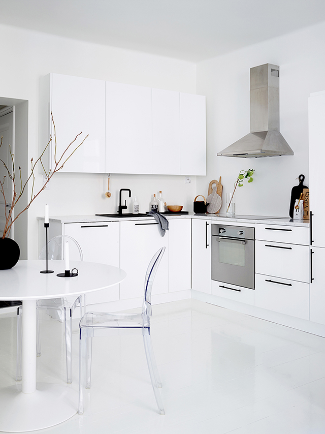The kitchen is modern and laconic, with black handles that create a graphic feature and a lucite chair