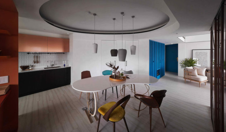 In the center of the apartment there's a dining zone accentuated with a ceiling and pendant lamps