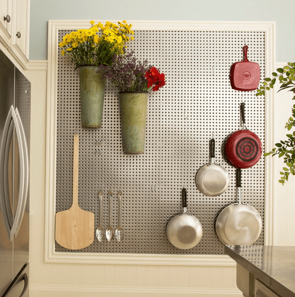 framed metal pegboard with hooks for utensils and metal pots attached