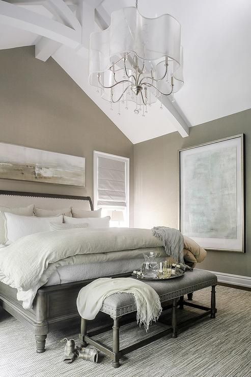taupe and gray bedroom features a wall painted taupe lined with a gray and taupe abstract panorama art placed above a wood sleigh bed