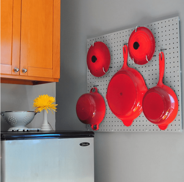 metal pegboard with hot red pans and frying pans looks like a decoration