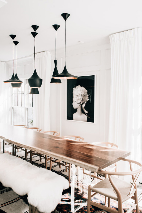 A composition of hanging black lamps and a dark artwork accentuate the subtle shade space