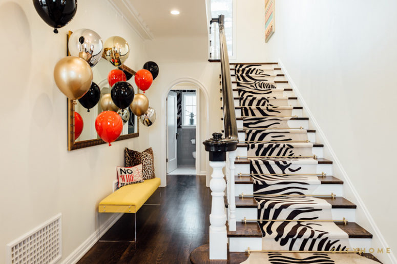 The entryway surprises with a bold yellow bench, balloons and a zebra print rug