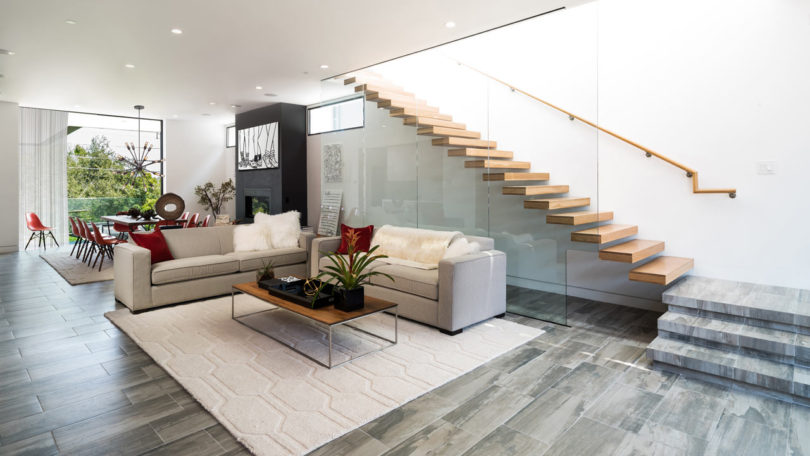 The floors are covered with grey and beige tiles, and the staircase is exciting, of wood and glass, looks very modern
