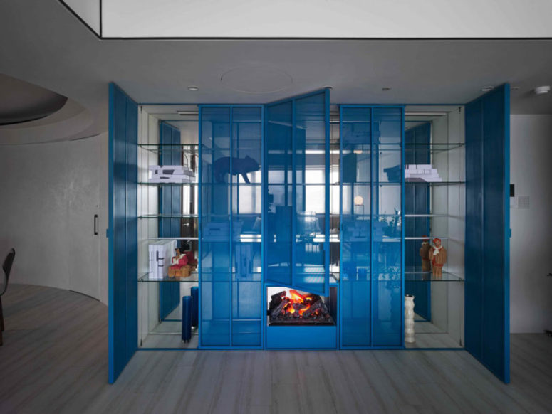 There's a bold blue sheer storage unit with a built in fireplace, such an interesting solution