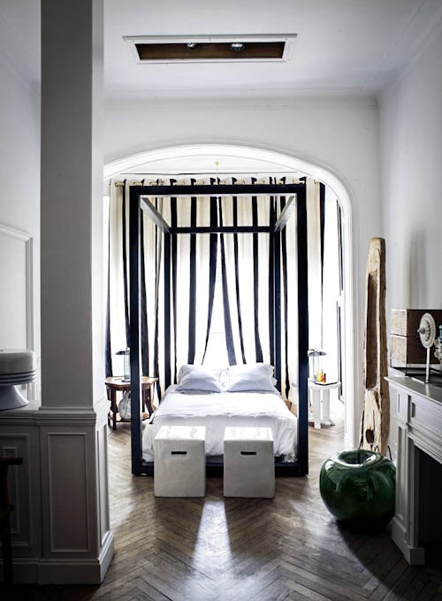 The bedroom is full of light, there's a large frame bed placed under an arched ceiling