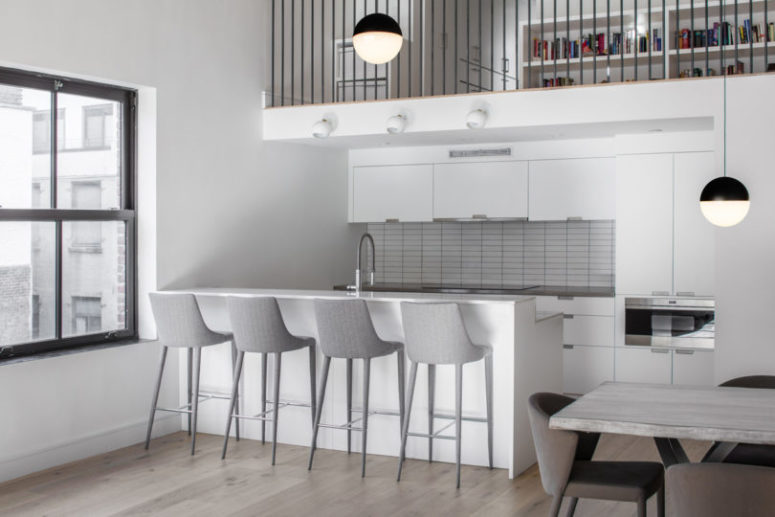 The kitchen is small and neutral, done in white and light grey, with a kitchen island as a breakfast nook