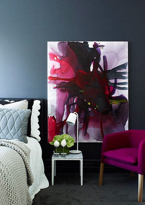 this bedroom is enlivened with a fuchsia chair and a unique wall art