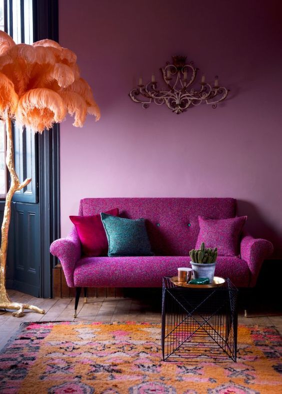 Mid century styled sofa in fuchsia color and a light pink wall look harmonious together