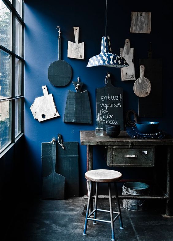 Indigo accent wall with antique cutting boards in a vintage and industrial kitchen
