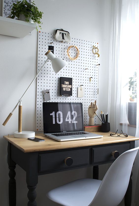 white pegboard with hooks for storage over the desk