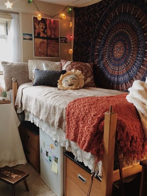 Boho and vintage inspired dorm room with a patterned rug on the wall and crochet blankets