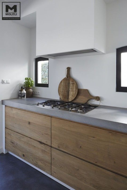 minimalist kitchen with concrete countertops and warm wood drawers