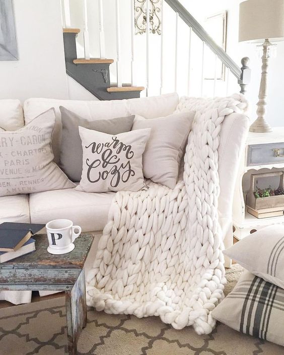 cozy white sofa with neutral pillows and a white chunky knit blanket
