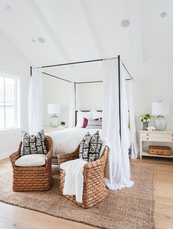 Beach inspired bedroom with a thin metal frae bed and airy white curtains
