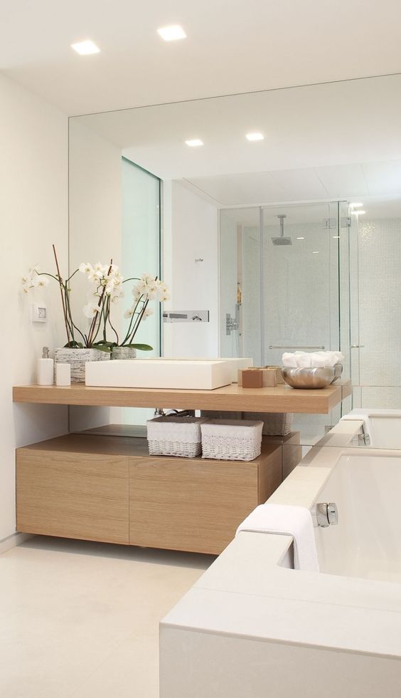Modern bathroom decor in white and light colored woods, a whole mirror wall