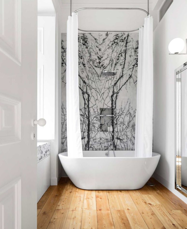 The bathroom catches an eye due to the use of Portuguese marble and a warm-colored wooden floor