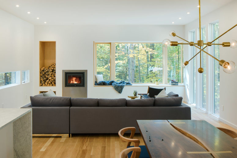 The living room features a comfy sofa next to the fireplace and firewood storage, there's a window sill to dream on it